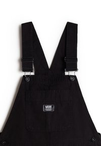 Schwarze Latzhosen mit verstellbaren Trägern, silbernen Beschlägen, einer Fronttasche und einem Logopatch. Ausgestattet mit einem robusten Stoff und einem eleganten Design.