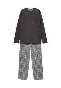Maglietta a maniche lunghe grigio scuro con taschino sul petto abbinata a pantaloni larghi a quadri grigi su sfondo bianco.