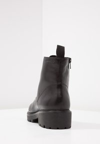 Svart ankelsko i mjukt läder med låg klack, sidodragkedja och en ögla för enkel påtagning.