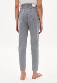 Korkeavyötäröiset, vaaleanharmaat farkut, joissa viisi taskua, suora lahjemalli ja haalistunut pinta. Vaatemerkin etiketti näkyy vyötäröllä.