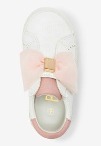Baskets blanches avec un nœud rose doux, des éléments en métal doré et un motif texturé. Doublure intérieure rose et détail du logo visibles. Éléments de design élégants.