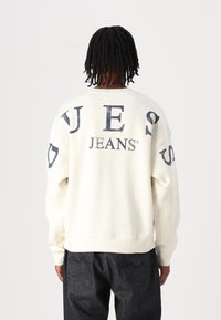 Felpa color crema con la scritta 