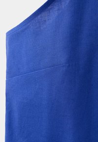 Tissu bleu avec un tissage texturé et un détail de couture horizontale, présenté en gros plan sur un fond clair uni.