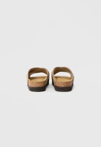 Sandali con suola in sughero marrone, con punta aperta e design a strap. Materiale superiore liscio, sottopiede morbido e forma minimalista.