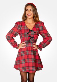 Rood geruit jurkje met poffende mouwen en een diepe V-hals. Bevat zwarte lintaccenten en een taille die is geaccentueerd, met een vloeiende rok.