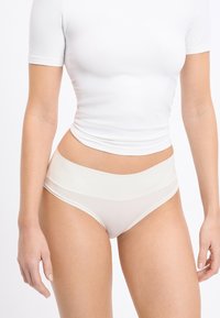 Light beige high-waisted underwear with a smooth texture and wide waistband. The fabric appears soft and elastic, shaped to fit comfortably.
