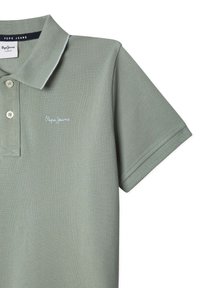 Polo verde realizzato in cotone testurizzato, caratterizzato da una chiusura a tre bottoni, maniche corte e un piccolo logo ricamato sul petto.