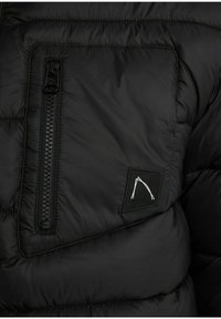 Sort polstret jakke sektion med en lynlås lomme og et logo patch. Har en quilted tekstur og et slankt design. Lynlåsen har en sort trækstrop.