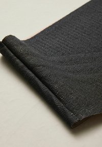 Black lace fabric with a textured, intricate pattern, folded neatly at one edge, showcasing a soft, delicate appearance.