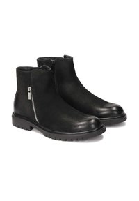 Botas negras de tobillo con parte superior de cuero suave, cierre de cremallera y suela de goma texturizada con un patrón de banda de rodadura resistente.