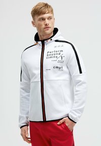 Felpa bianca con zip, decorata con dettagli neri e arancioni. Presenta testo stampato, cappuccio e tasche. Texture liscia e vestibilità sportiva.