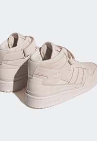 Light beige suede high-top sneakers with a smooth texture, featuring three stripes and a logo on the side, and a cushioned collar.