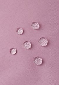 Gocce d'acqua su una superficie di tessuto rosa testurizzato, caratterizzate da piccole forme rotonde con riflessi chiari e una finitura liscia.