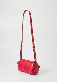Rote Lederhandtasche in rechteckiger Form, mit abnehmbarem Tragegurt, Hardware in goldfarbener Ausführung und einer Seitentasche mit Klappe.