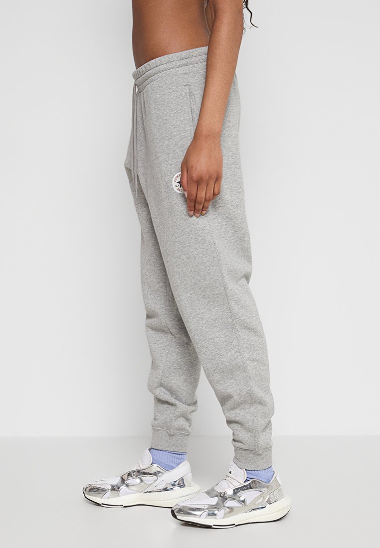 Szare bawełniane spodnie dresowe o tapered fit, z bocznymi kieszeniami i nadrukowaną naszywką z logo na udzie. W zestawie z metalicznymi sneakersami.
