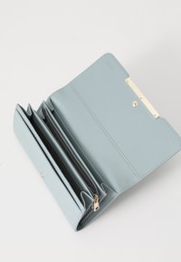 Light blue wallet made of smooth leather, featuring multiple card slots, a zip compartment, and a gold-tone clasp with textured detail.