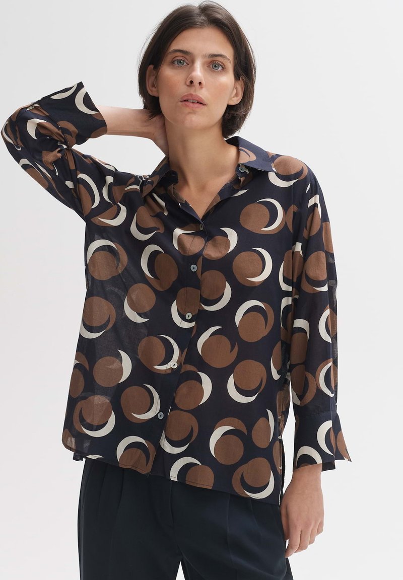 Camicia blu navy con bottone, caratterizzata da un motivo circolare in marrone e crema. Realizzata in un tessuto leggero, presenta maniche lunghe e una vestibilità comoda.