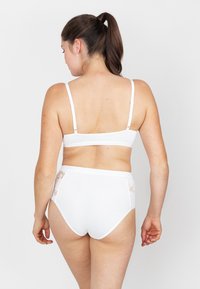 Witte lingerie set met een eenvoudige beha en hooggeremde onderbroek. De onderbroek heeft kanten accenten aan de zijkanten, wat een zacht ontwerp benadrukt.