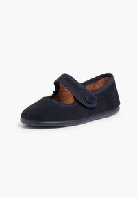 Zapato Mary Jane de gamuza en color azul marino con punta redonda, correa elástica y plantilla texturizada en color marrón. Presenta un botón de acento sutil y suela de goma.