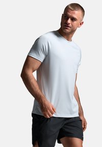 Camiseta deportiva azul claro hecha de tela suave que absorbe la humedad. Cuenta con mangas cortas y cuello redondo, combinada con pantalones cortos negros.