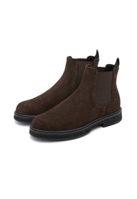 Botas Chelsea de ante marrón con diseño tipo slip-on, paneles laterales elásticos, suela texturizada negra y lengüetas en la parte trasera para ponerlas y quitarlas fácilmente.
