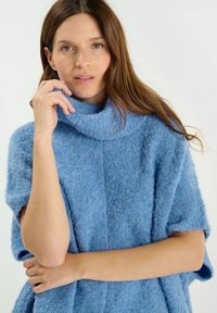 Pullover azzurro chiaro e accogliente con colletto alto e piegato. Realizzato in materiale morbido e texturizzato. Presenta maniche corte e una vestibilità rilassata.