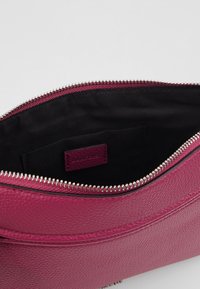 Clutch in pelle fucsia con finitura texturizzata, zip argentata e una piccola tasca interna con etichetta del marchio su fodera nera.