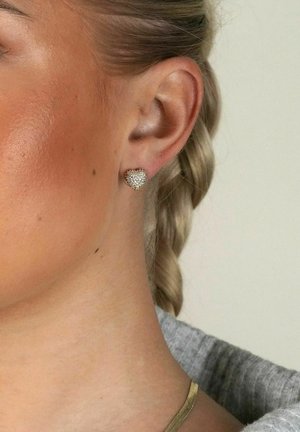 Hjärformade guldörhängen prydda med små klara rhinestones, som visar en texturerad yta och en polerad finish.