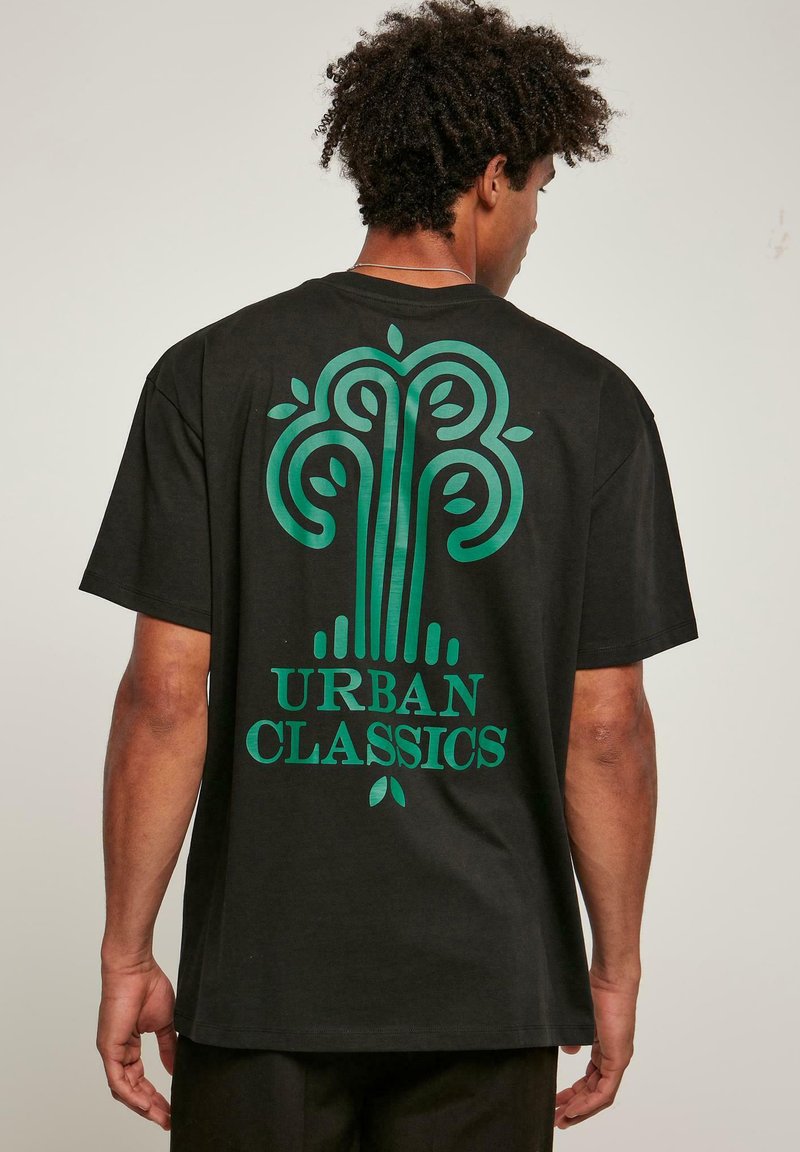 Juoda medvilninė marškinėliai su dideliu žaliu medžio dizainu ir "URBAN CLASSICS" tekstu ant nugaros. Trumpomis rankovėmis ir laisvu siluetu.