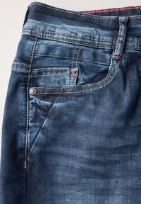 Mörkblå denim jeans med en slät yta, med sydda detaljer i kontrasterande tråd och en metallknapp på framlappen.