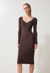 Brown ribbed midi dress with long sleeves, featuring a V-neckline and fitted silhouette. Textured fabric enhances overall design.