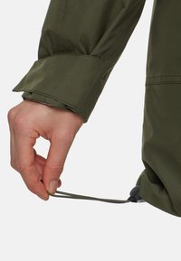 Olijfgroen waterdichte jas met een strakke trekkoord aan de zoom, met een gladde stoftextuur en een veilige togglesluiting.