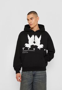 Black hoodie made of cotton with a front graphic featuring two white doves, text reading "LOST YOUTH," and a kangaroo pocket.