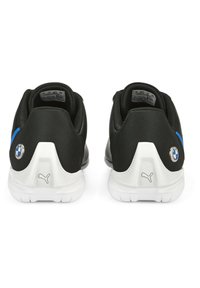 Fekete sportcipők, textúrált anyagból, fehér talppal, kék díszcsíkkal, BMW logóval és Puma logóval a sarkon.