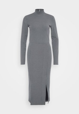 Vestido cinza canelado com gola alta e mangas longas, apresentando uma fenda lateral para facilitar o movimento e uma silhueta justa.