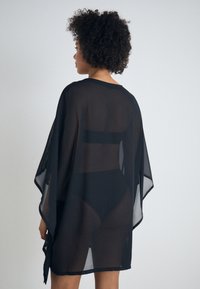 Čierny priesvitný kimono štýl plášť s širokými rukávmi a voľným strihom, s hladkou textúrou a otvoreným dizajnom na chrbte.