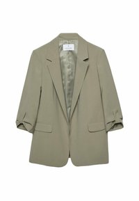 Ljus khaki blazer med spetsig krage, axelvaddar och två framfickor. Har uppkavlade ärmar och ett slätt innerfoder.