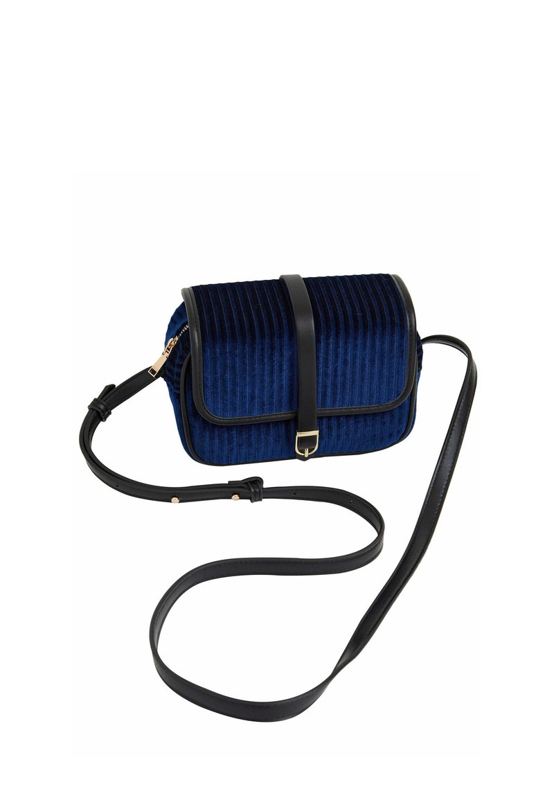 Navy blue corduroy crossbody bag with black leather accents, a flap closure, gold hardware, and an adjustable strap. Textured vertical lines.