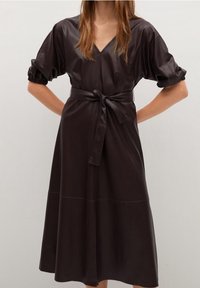Vestido de cuero marrón oscuro con escote en V, mangas cortas abullonadas y un cinturón a juego en la cintura. Presenta una falda acampanada y una textura suave.