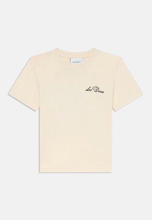 Korte mouwen crème t-shirt van katoen, met een zwart geborduurd "Les Deux" logo op de linkerkant van de borst. Glad textuur, reguliere pasvorm.