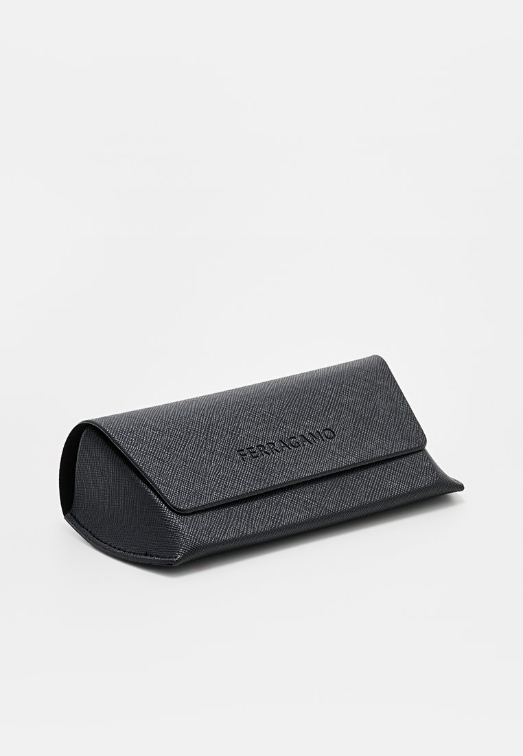 Funda dura texturizada negra con cierre de solapa, que presenta un logo de marca en relieve. Bordes redondeados y diseño resistente. Adecuada para almacenar gafas.