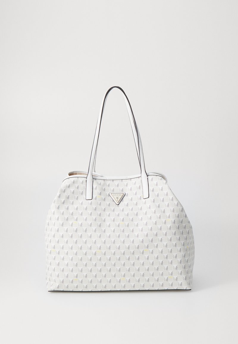 Sac à main blanc avec un motif géométrique en gris et jaune. Dispose de deux poignées et d'un logo en métal triangulaire à l'avant.