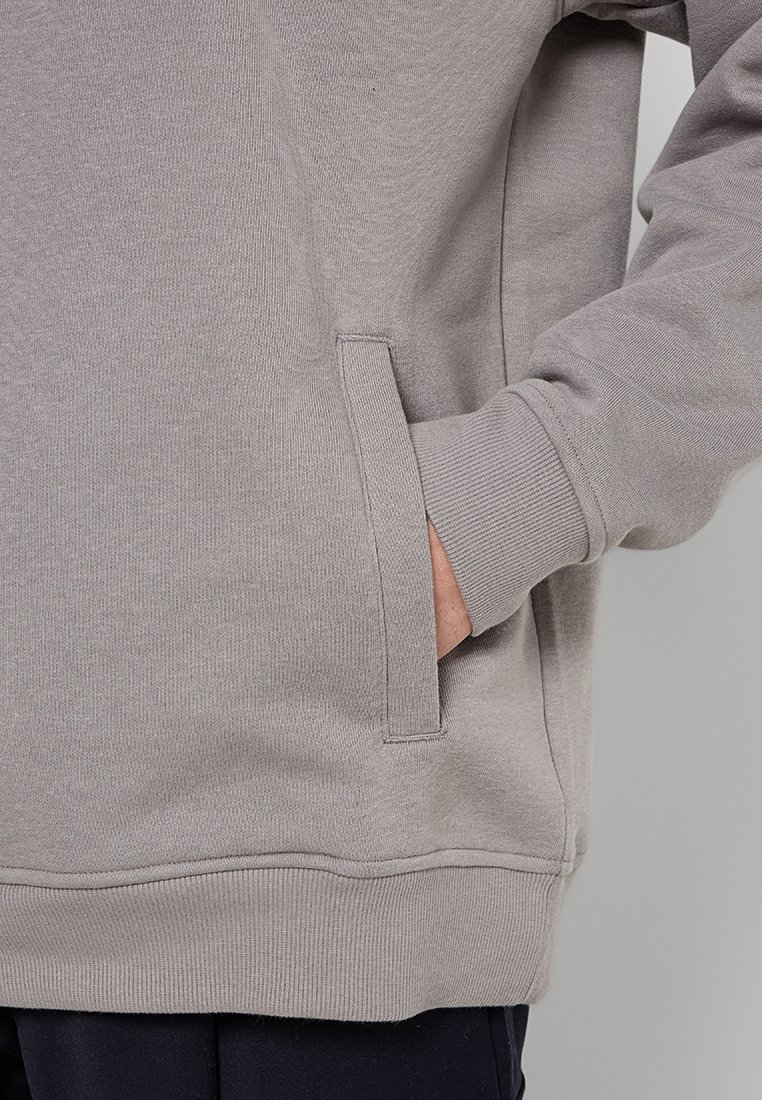 Grijze sweatshirt van een textuurstof, met een zijzak en geribbelde manchetten. De zoom is licht elastisch voor een aansluitende uitstraling.