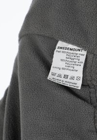 Grå fleece stof med en blød tekstur, der har et plejetikette. Indeholder materialer: 100% polyester skal og for med polyurethan-beskyttelse.