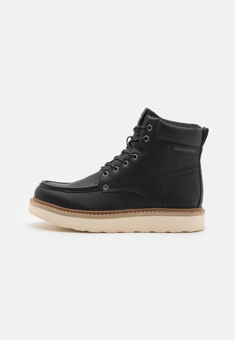 Bottines en cuir noir avec semelle en caoutchouc beige, bout arrondi et design à lacets. Présente des détails de couture et un marquage sur le côté.