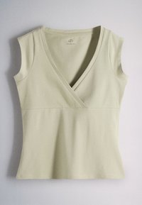 Sleeveless light beige women's top with a deep V-neck and fitted waist, made of soft fabric, laid flat against a light background.