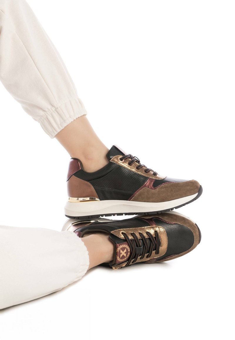 Las zapatillas negras, marrones y doradas presentan una combinación de materiales de cuero y ante, con un acabado texturizado, un cuello acolchado y adornos decorativos.