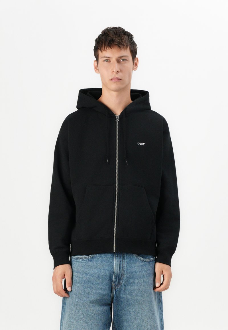 Black zip-up hoodie made of soft fabric, features a front pocket, drawstring hood, and small white "OBEY" logo on the left chest.