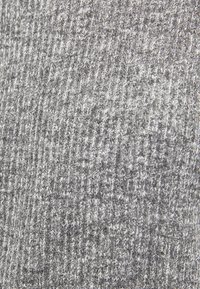 Tissu tricoté gris avec un motif côtelé texturé. Le matériau présente une apparence douce avec des nuances variées de gris clair et foncé.