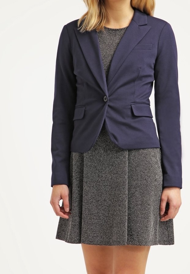 Blazer navy entallado con cierre de un solo botón, dos bolsillos frontales y solapas estructuradas, combinado con un vestido gris texturizado con falda acampanada.